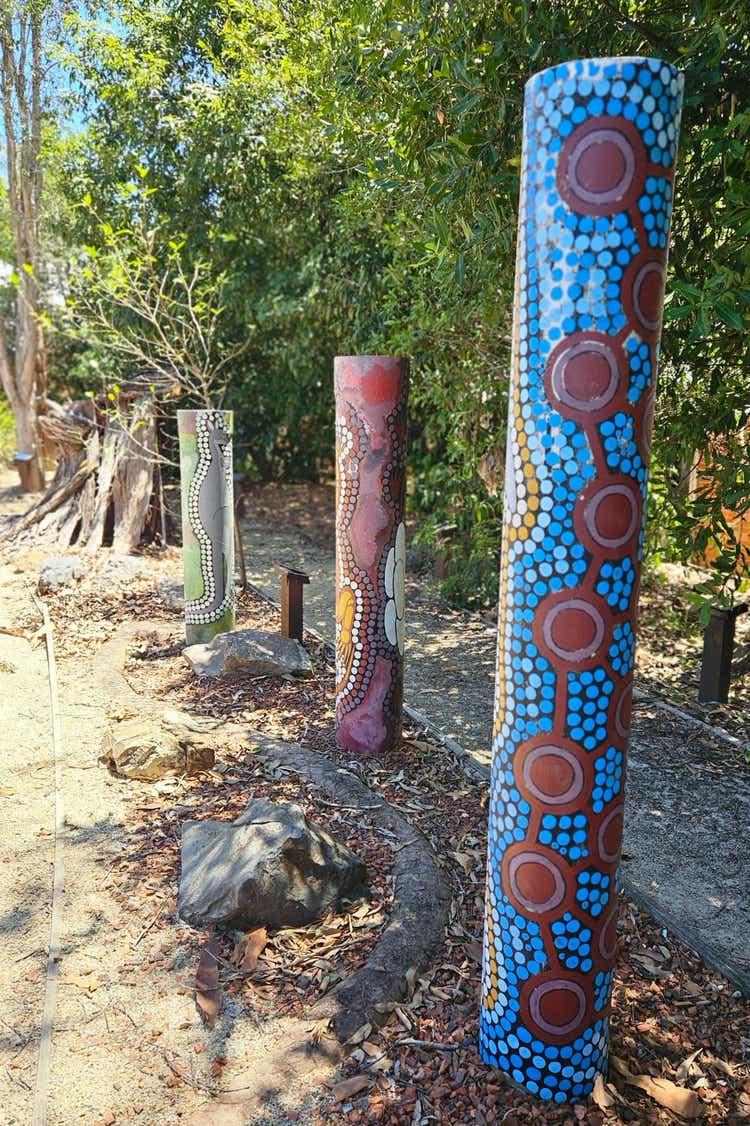 Schools indigenous garden featuring three totem poles with indigenous artworks.