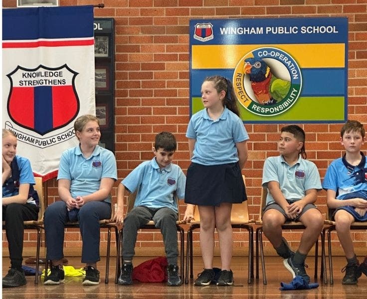 Students participating in the spelling bee, up on stage in the school hall.